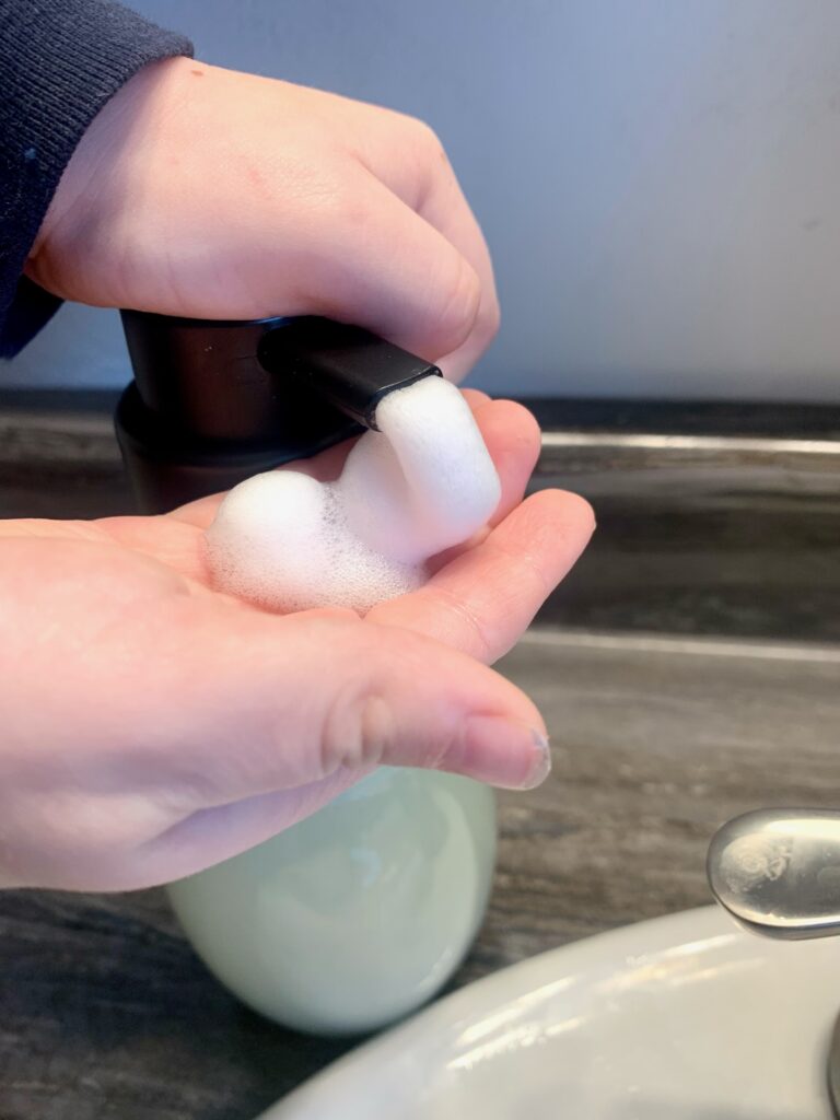 Little Boy's hands getting foaming hand soap.