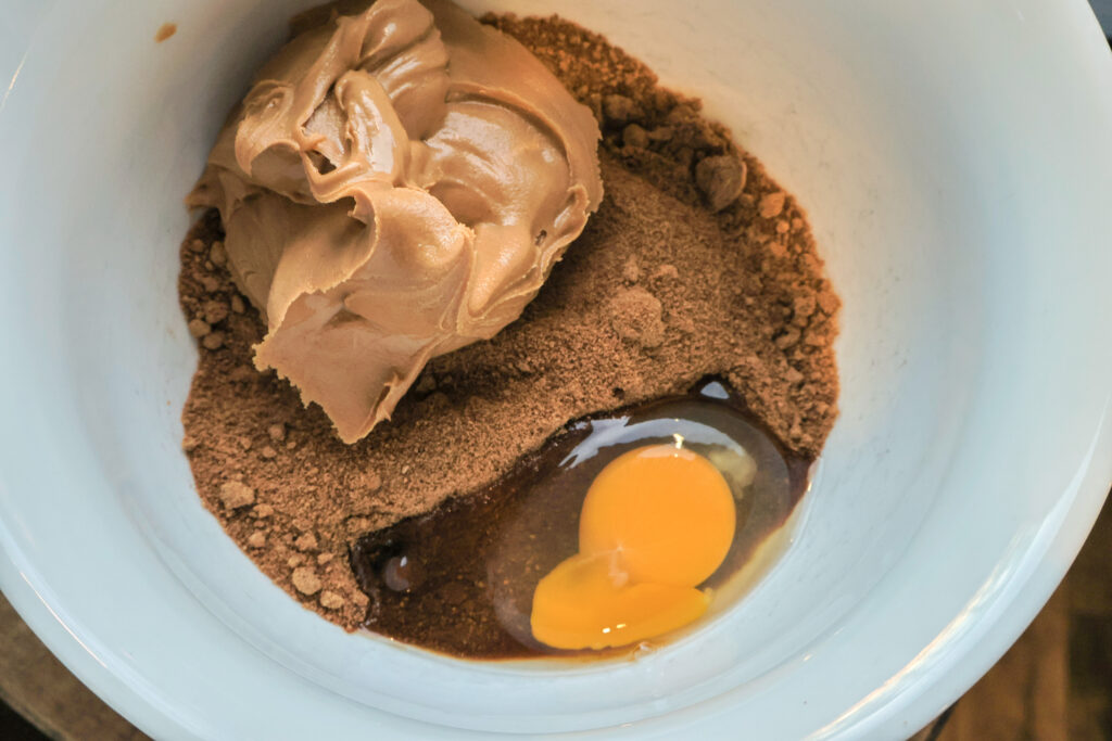 Coconut sugar, peanut butter and egg in white bowl