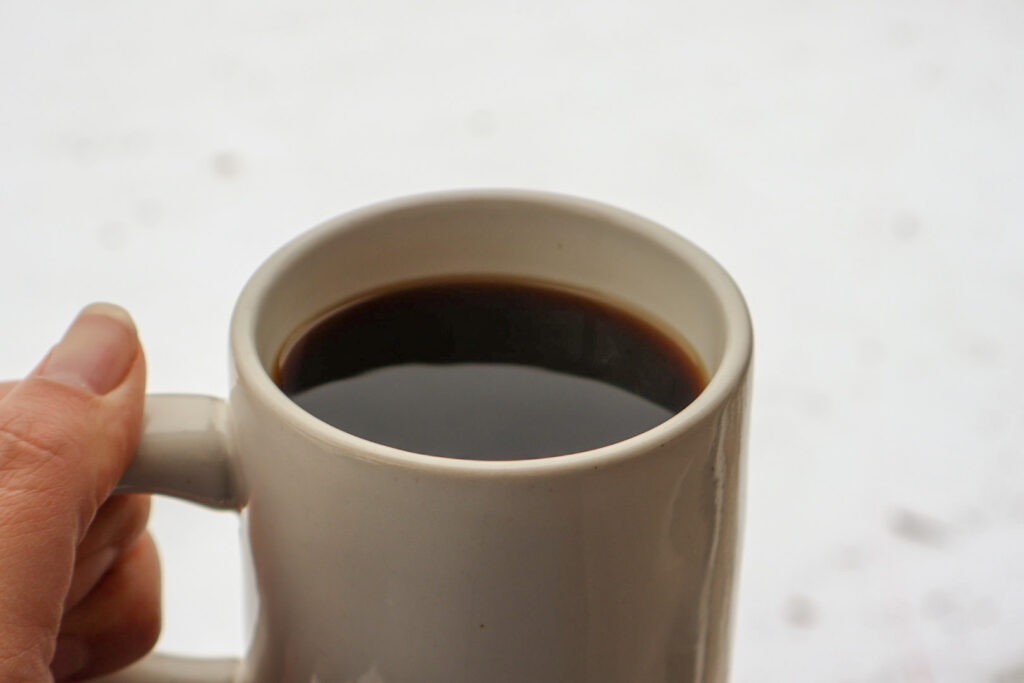 Holding a cup of coffee with a snowy background