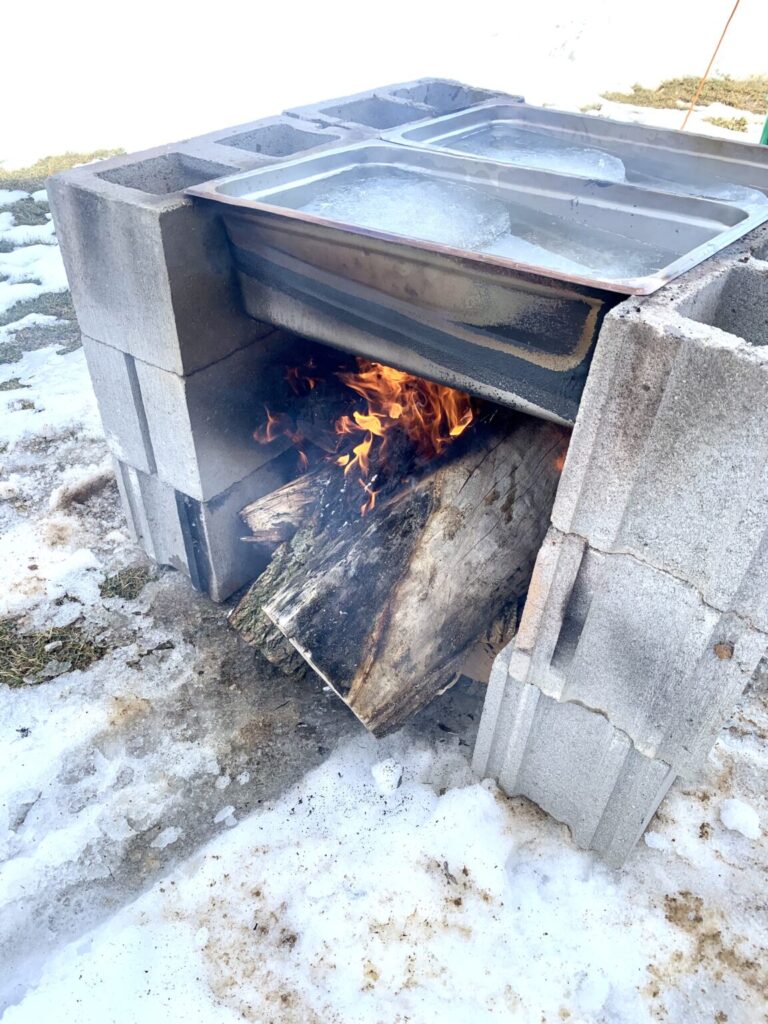 Boiling sap over a fire with banquet pans and cinder blocks