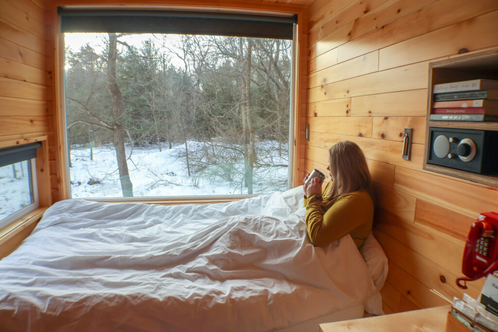 Women sitting in bed drinking a coffee looking out the window
